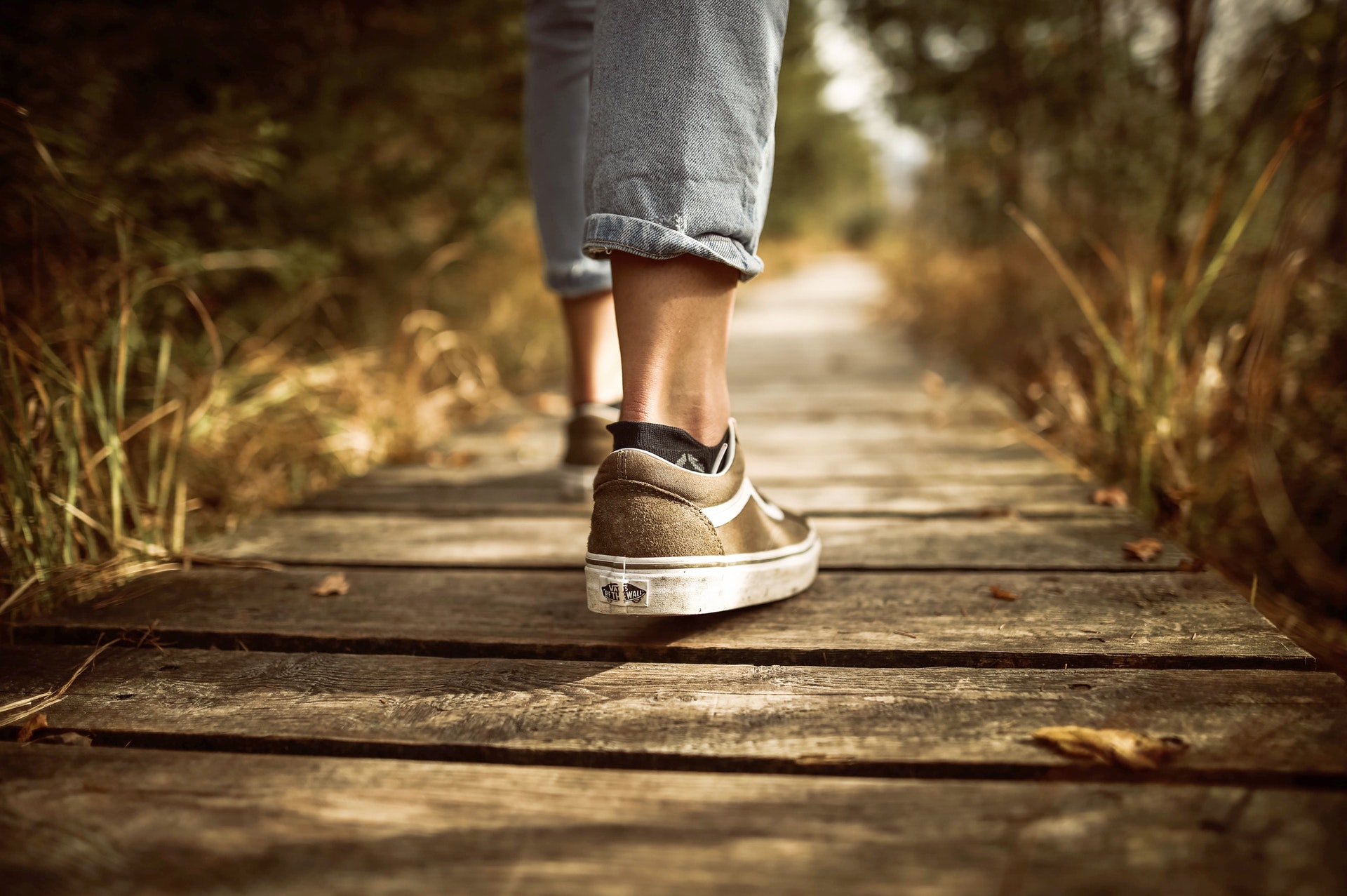 A person's legs walking along a wooden path